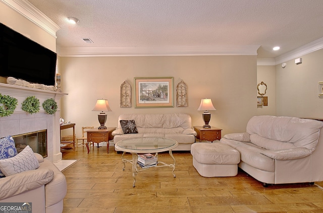 living room featuring crown molding, a fireplace, light hardwood / wood-style floors, and a textured ceiling