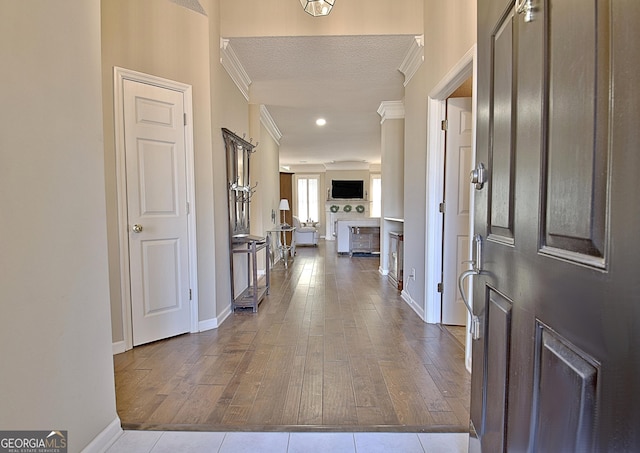 entrance foyer featuring crown molding, light hardwood / wood-style floors, and a textured ceiling