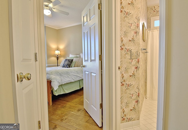 bedroom featuring ceiling fan, ornamental molding, light hardwood / wood-style floors, and a textured ceiling