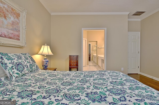 bedroom featuring ornamental molding, ensuite bathroom, and light hardwood / wood-style floors