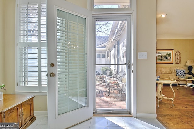 entryway with light tile patterned floors and crown molding