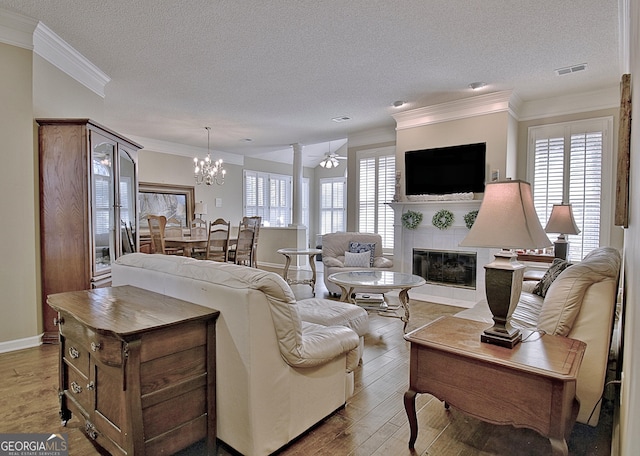 living room featuring a tiled fireplace, crown molding, hardwood / wood-style flooring, and a wealth of natural light