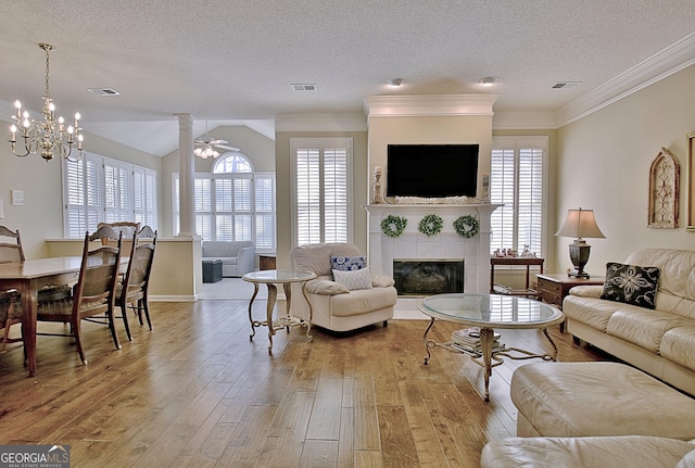 living room featuring a tile fireplace, ceiling fan, a textured ceiling, and light hardwood / wood-style flooring