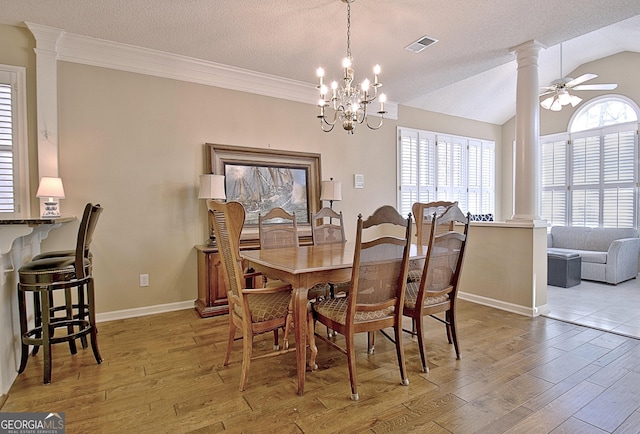 dining area featuring decorative columns, vaulted ceiling, and light hardwood / wood-style floors