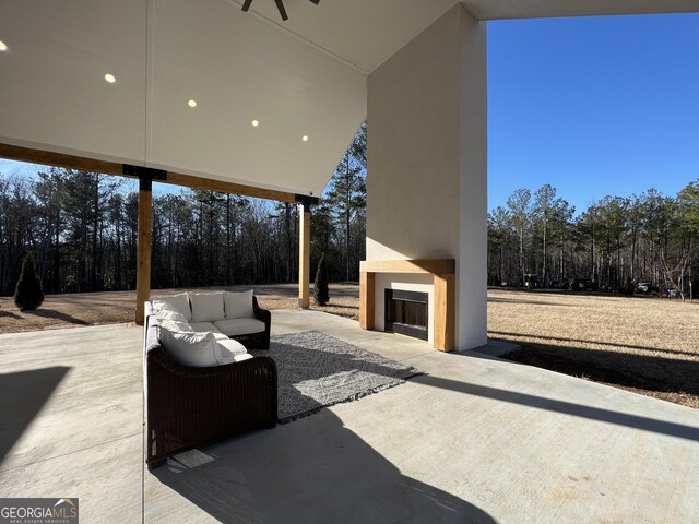 view of patio / terrace featuring ceiling fan and an outdoor living space with a fireplace