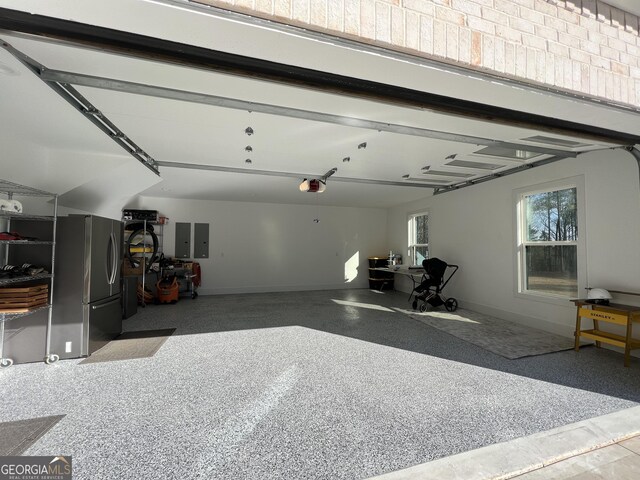 garage featuring electric panel, a garage door opener, and stainless steel refrigerator