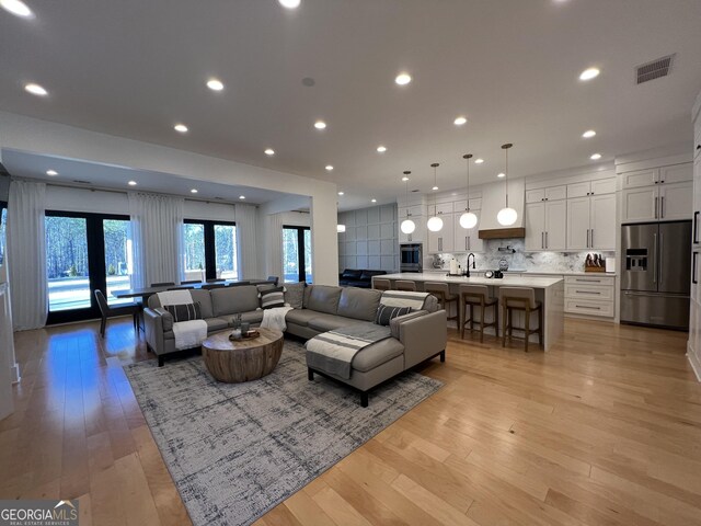 living room featuring light hardwood / wood-style floors, sink, and french doors