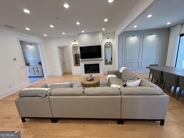 living room featuring light wood-type flooring and a large fireplace