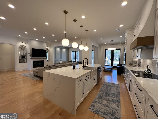 kitchen featuring premium range hood, sink, hanging light fixtures, appliances with stainless steel finishes, and a large island