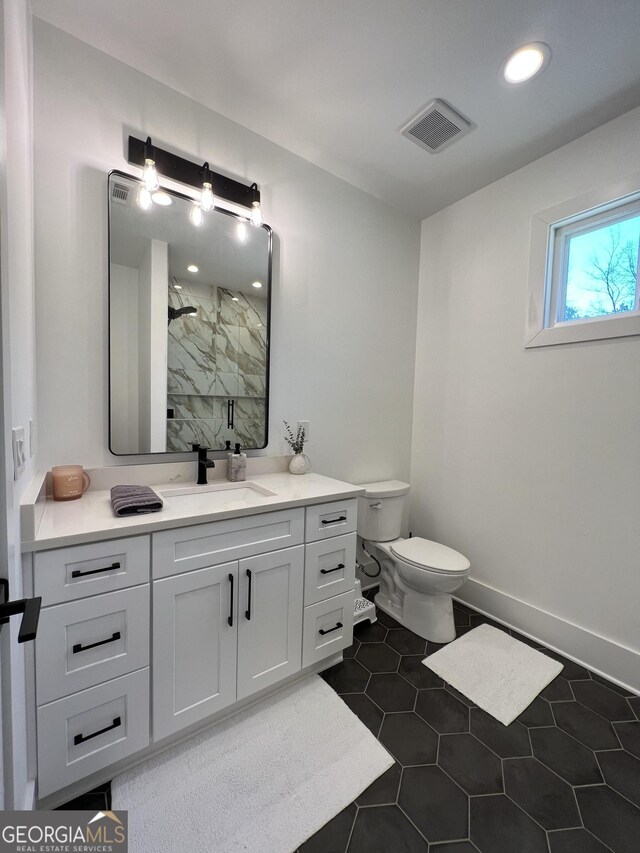 bathroom featuring toilet, a shower, tile patterned floors, and vanity