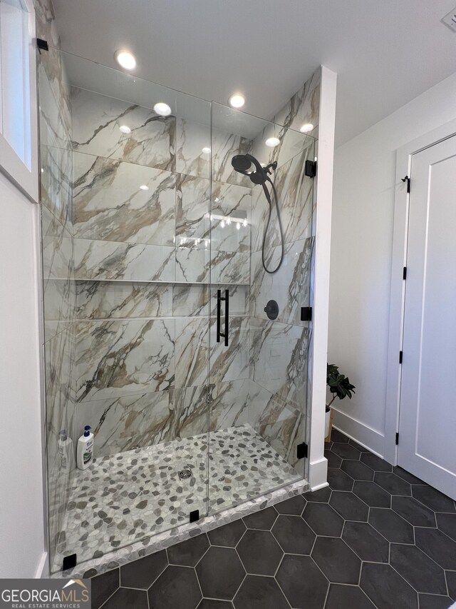 bathroom with a shower with door and tile patterned flooring