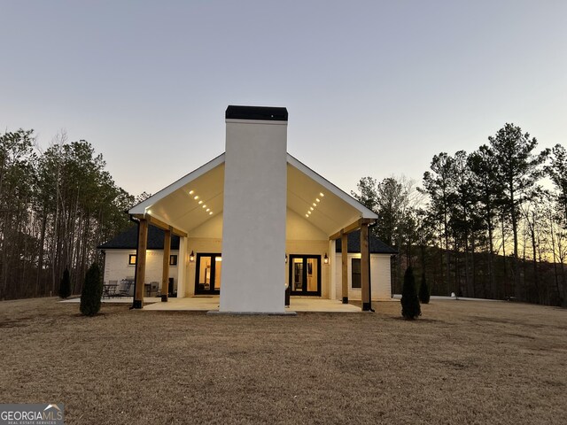 back house at dusk with a yard and a patio