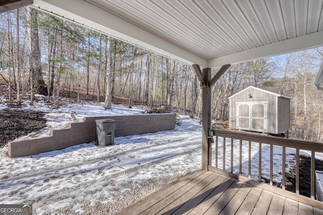 snow covered deck featuring a storage shed