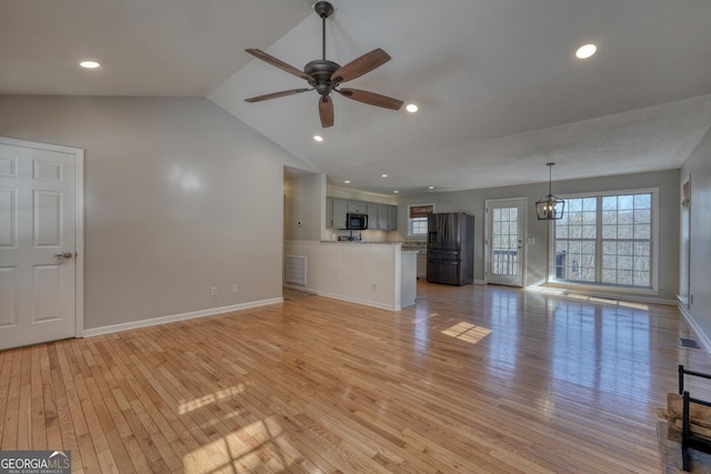 unfurnished living room with ceiling fan, lofted ceiling, and light wood-type flooring