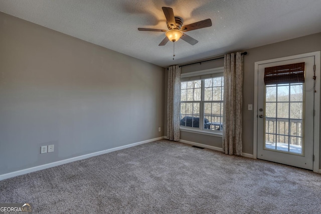 carpeted spare room with ceiling fan, a textured ceiling, and a wealth of natural light