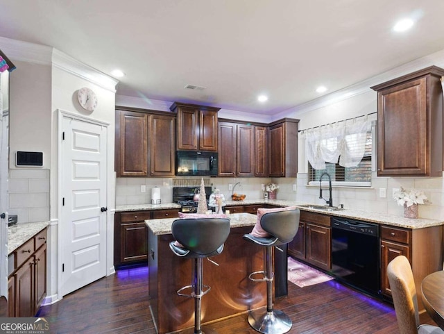 kitchen featuring dark hardwood / wood-style floors, a center island, light stone countertops, black appliances, and sink