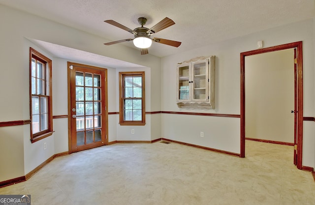 unfurnished room with ceiling fan and a textured ceiling