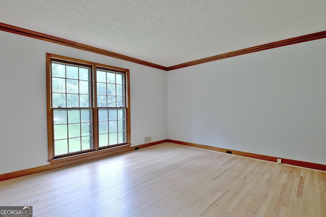 empty room featuring light wood-type flooring, a textured ceiling, and ornamental molding