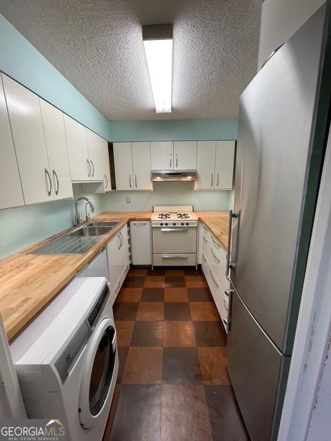 kitchen with sink, wooden counters, white appliances, washer / clothes dryer, and white cabinets