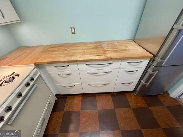 kitchen featuring wooden counters, stainless steel refrigerator, white cabinetry, and white range with gas cooktop