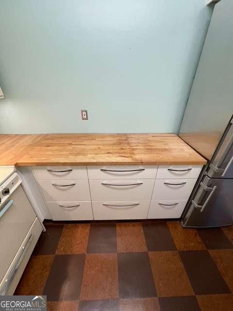 interior details featuring white cabinets, butcher block countertops, and refrigerator