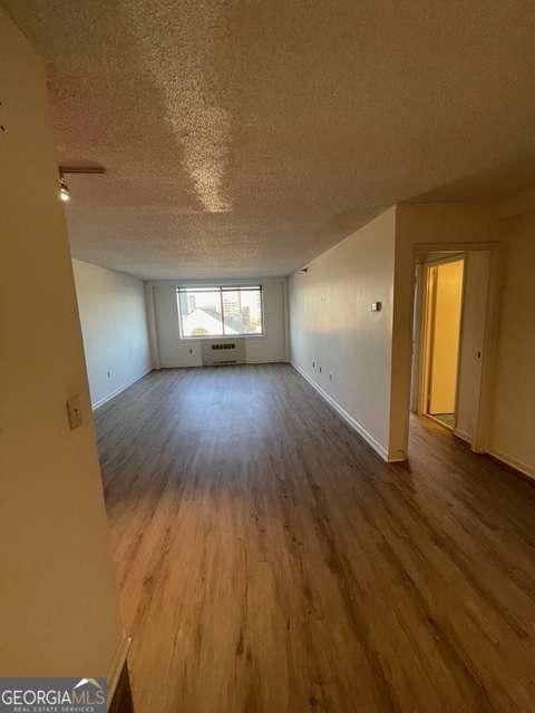 empty room with a textured ceiling, hardwood / wood-style flooring, and a wall mounted air conditioner