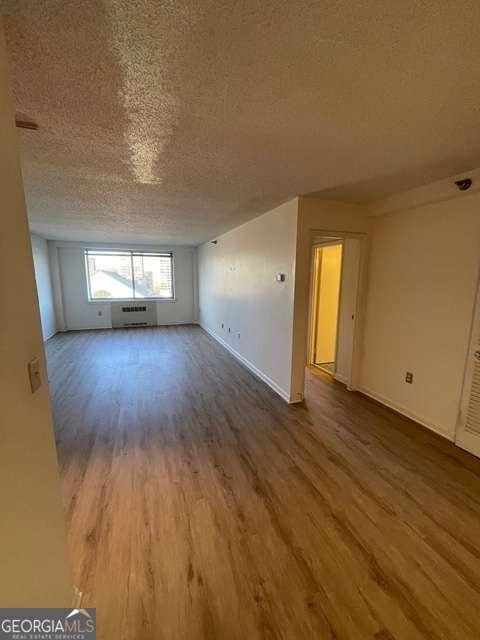 empty room featuring a textured ceiling, a wall mounted AC, and wood-type flooring