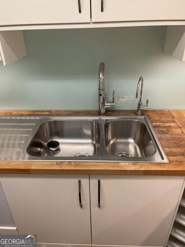 room details with wood counters, white cabinets, and sink