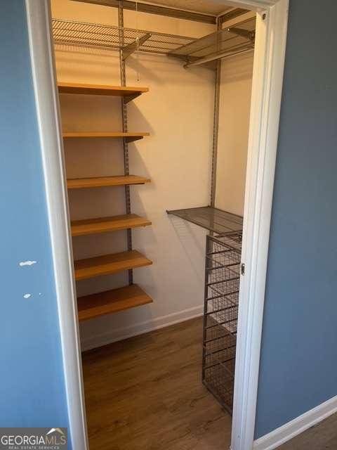 walk in closet with dark hardwood / wood-style flooring