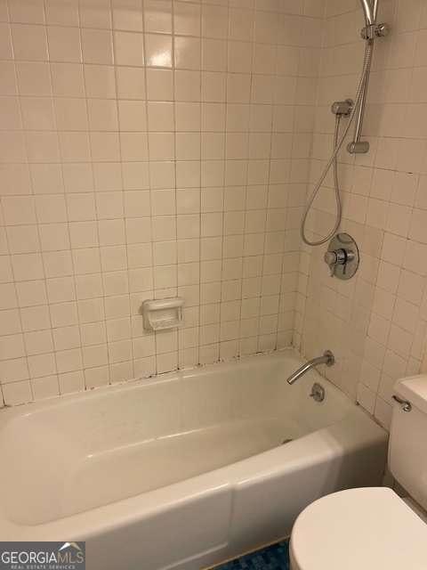 bathroom featuring toilet and tiled shower / bath combo