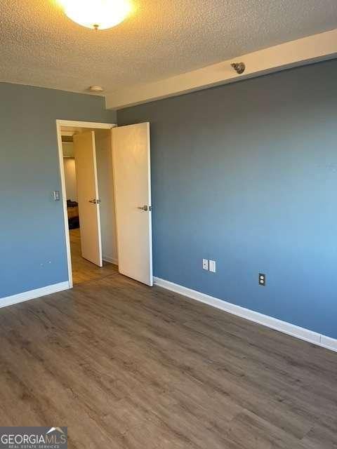 empty room featuring a textured ceiling and dark hardwood / wood-style flooring