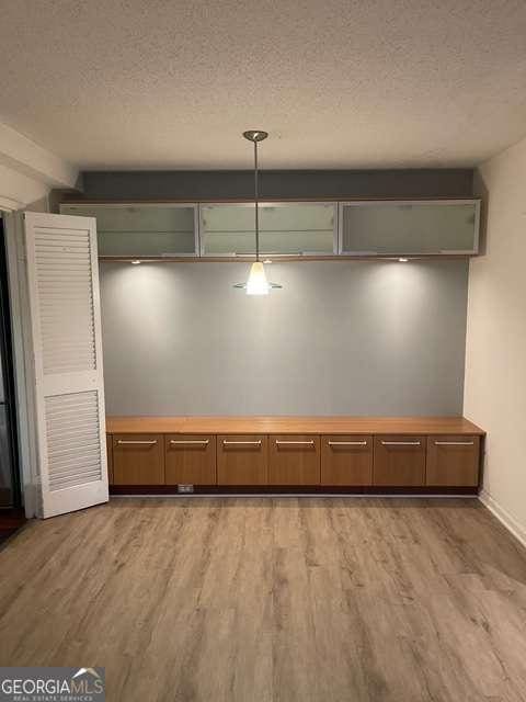 interior space featuring a textured ceiling, hardwood / wood-style floors, and hanging light fixtures