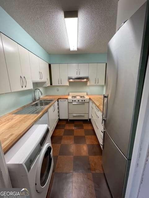 kitchen featuring white cabinets, white appliances, and washer / dryer