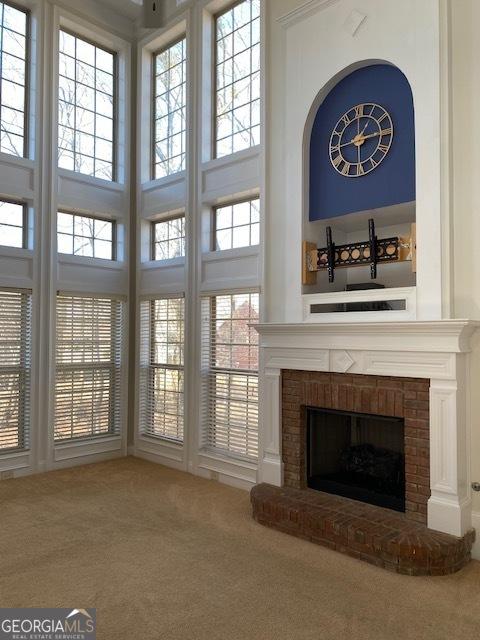 unfurnished living room with carpet floors, a fireplace, and a towering ceiling