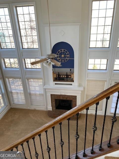 staircase with a high ceiling, ceiling fan, and a fireplace