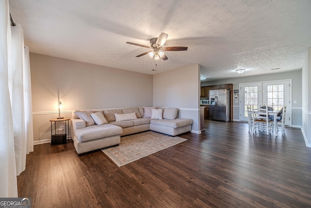 living room featuring ceiling fan, dark hardwood / wood-style floors, and a textured ceiling