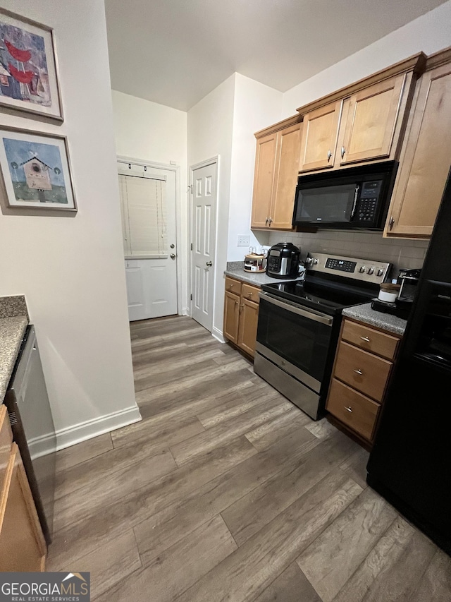 kitchen featuring dark wood-type flooring, backsplash, and black appliances