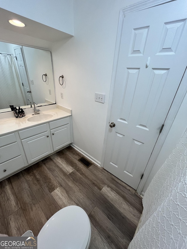 bathroom with hardwood / wood-style flooring, toilet, and vanity