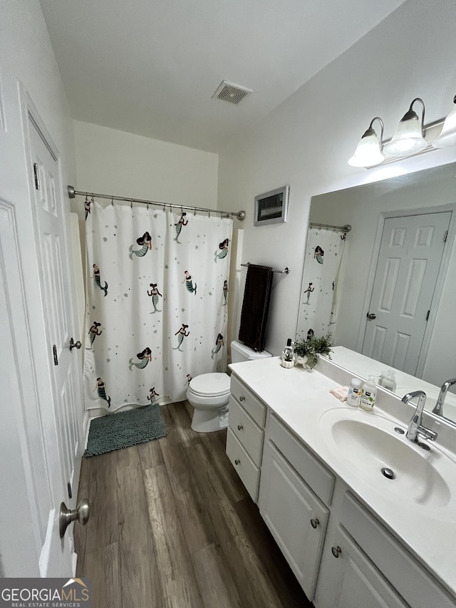 bathroom with hardwood / wood-style floors, toilet, vanity, and a shower with curtain