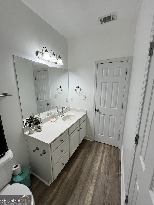 bathroom featuring hardwood / wood-style flooring, toilet, and vanity