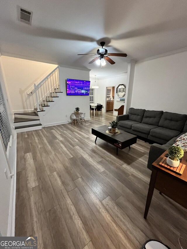 living room with ceiling fan, wood-type flooring, and ornamental molding