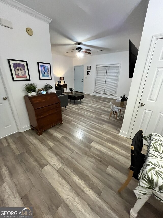 interior space featuring ceiling fan, ornamental molding, and wood-type flooring