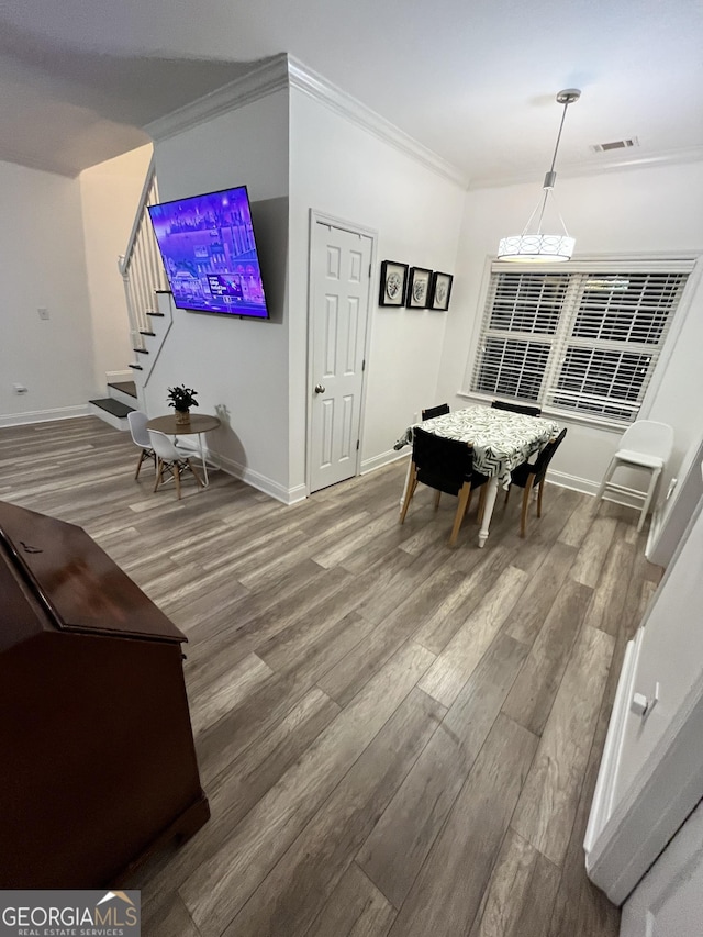 dining area with hardwood / wood-style flooring and crown molding