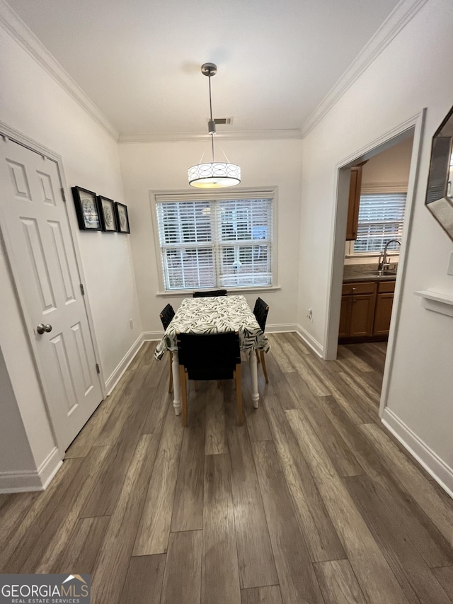 dining area with dark wood-type flooring, sink, and crown molding