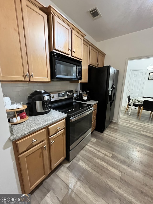 kitchen featuring black appliances, light hardwood / wood-style floors, and tasteful backsplash