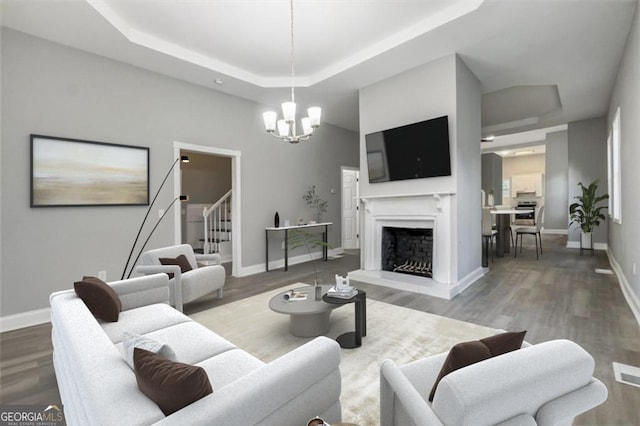 living room featuring an inviting chandelier, hardwood / wood-style floors, and a raised ceiling