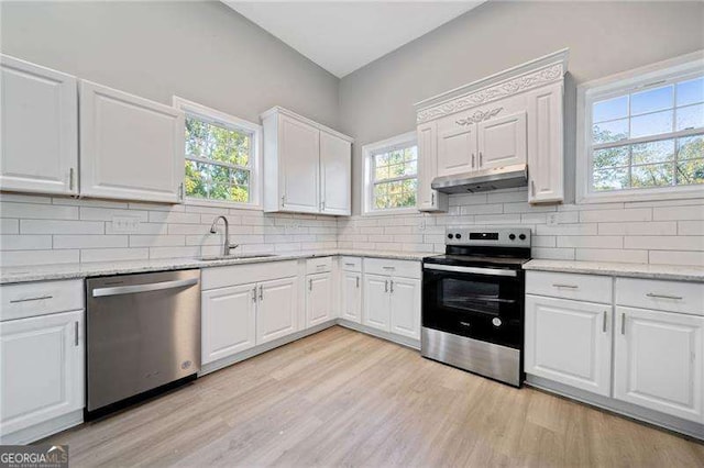 kitchen featuring appliances with stainless steel finishes, decorative backsplash, white cabinets, light stone counters, and sink