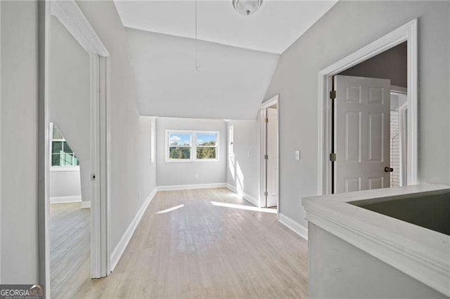 hall featuring lofted ceiling, a healthy amount of sunlight, and light hardwood / wood-style floors