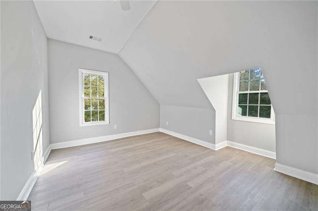 bonus room with light wood-type flooring and vaulted ceiling