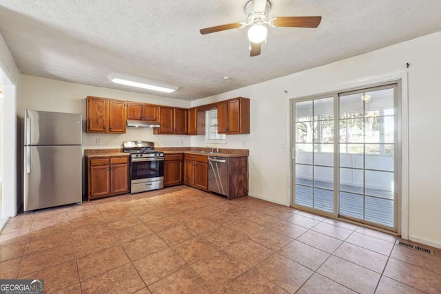 kitchen featuring light tile patterned flooring, ceiling fan, stainless steel appliances, and a textured ceiling